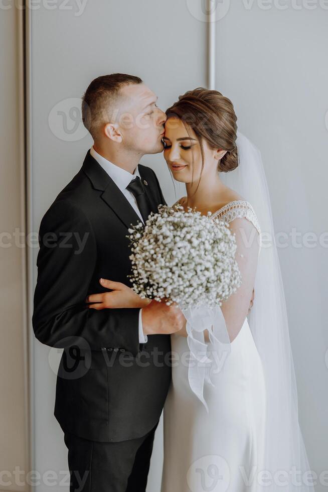 A bride and groom are hugging and kissing each other photo