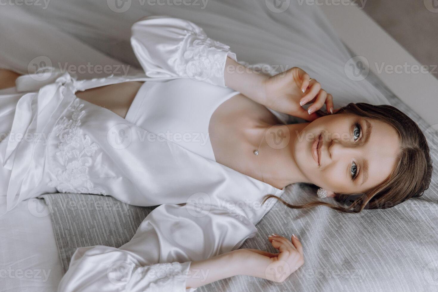 A woman is laying on a bed in a white robe photo