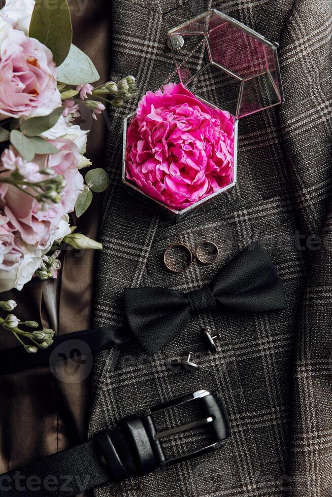 A man's outfit is adorned with a pink flower, a tie, and a bow photo