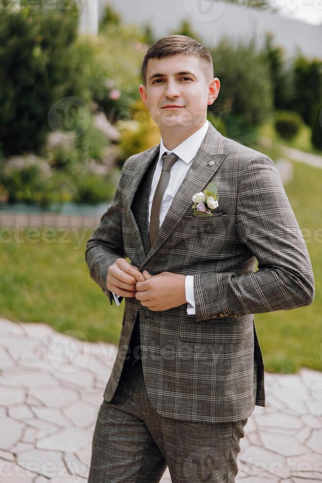 A man in a suit and tie is standing in a garden photo