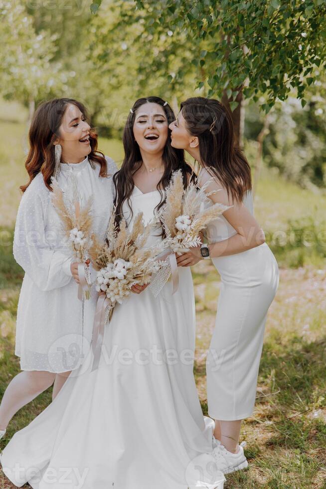 Three women are posing for a photo, with one of them wearing a white dress photo