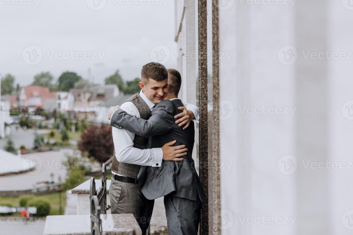 Two men hug each other on a balcony photo