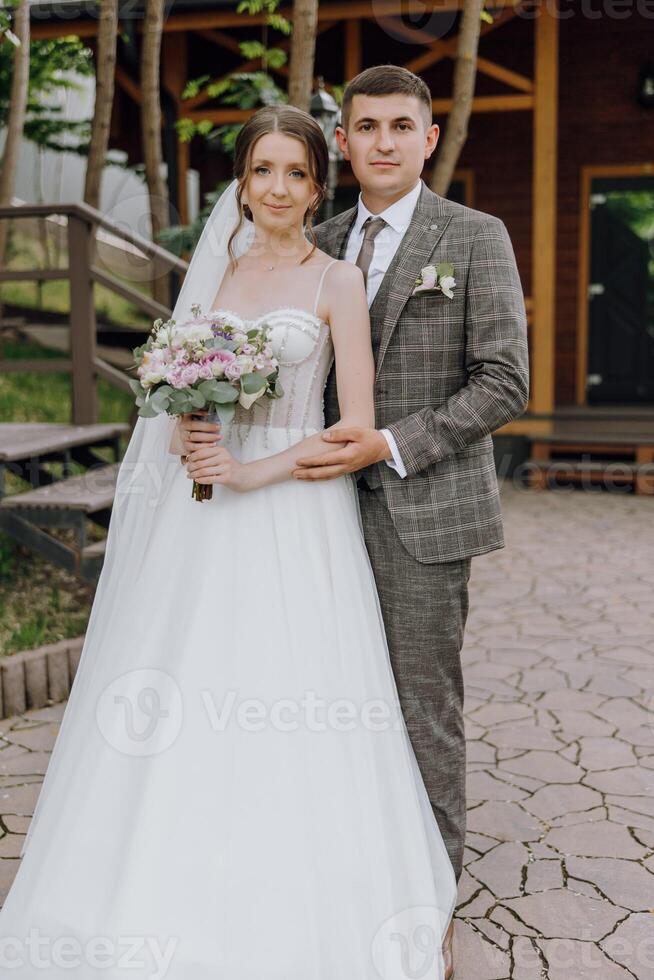 A bride and groom are posing for a picture in front of a wooden building photo