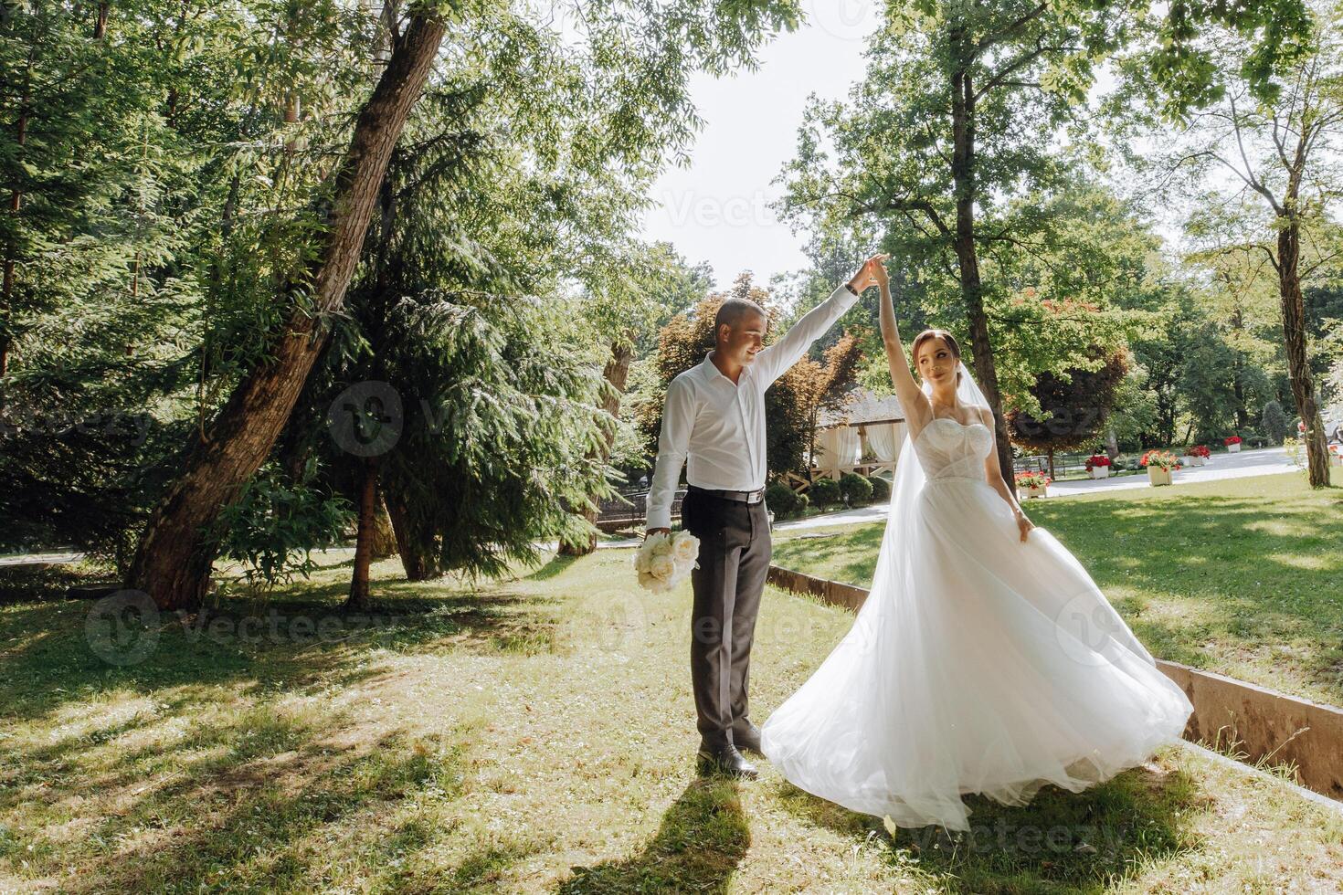 A bride and groom are dancing in a park photo