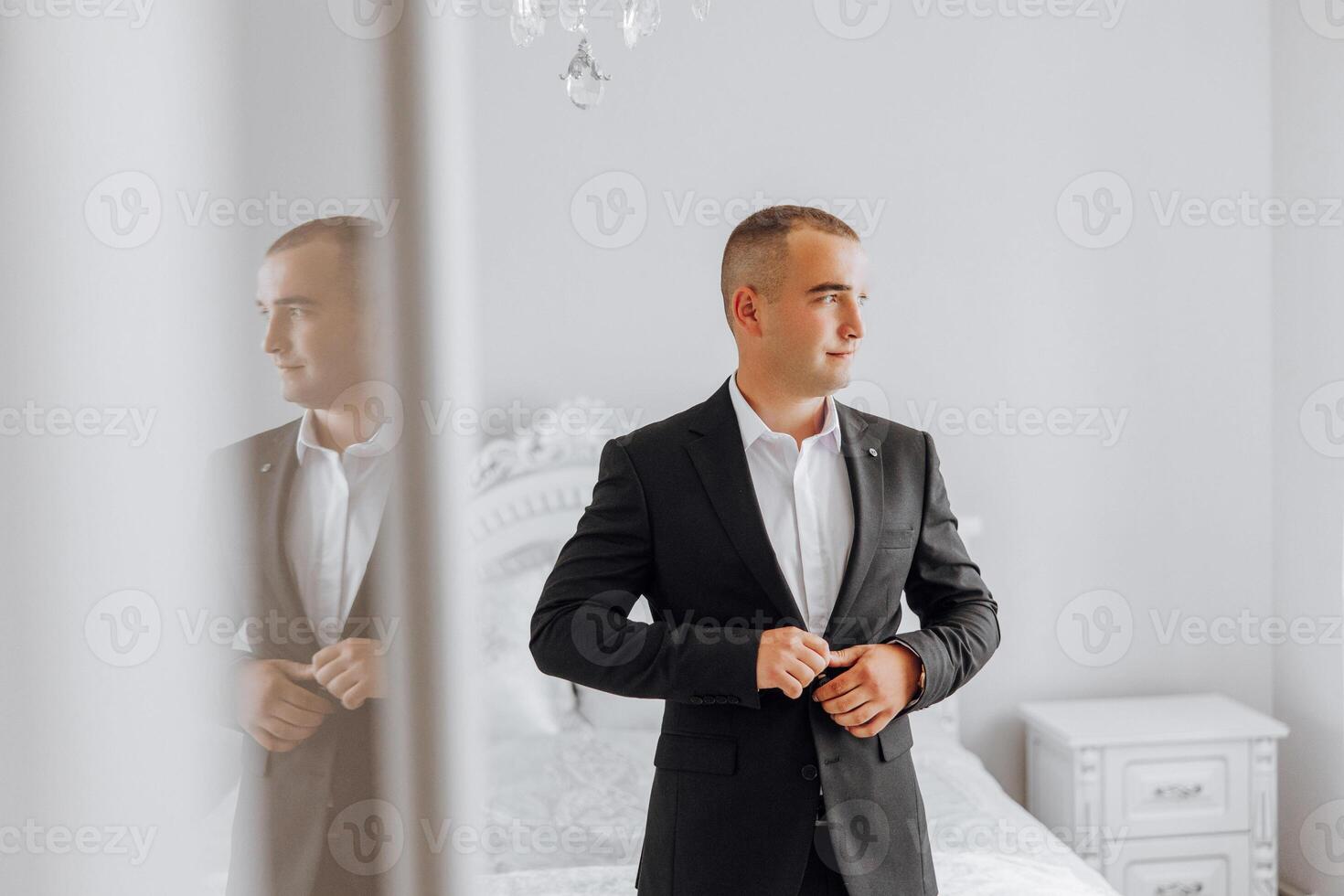A man in a suit is standing in front of a bed photo