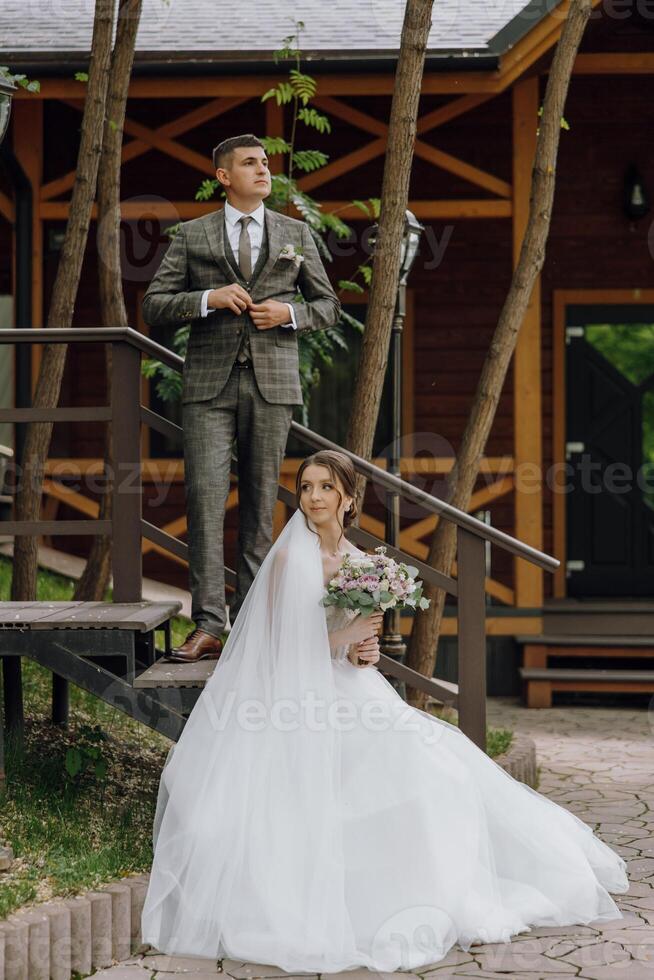 A bride and groom are standing on a wooden staircase photo