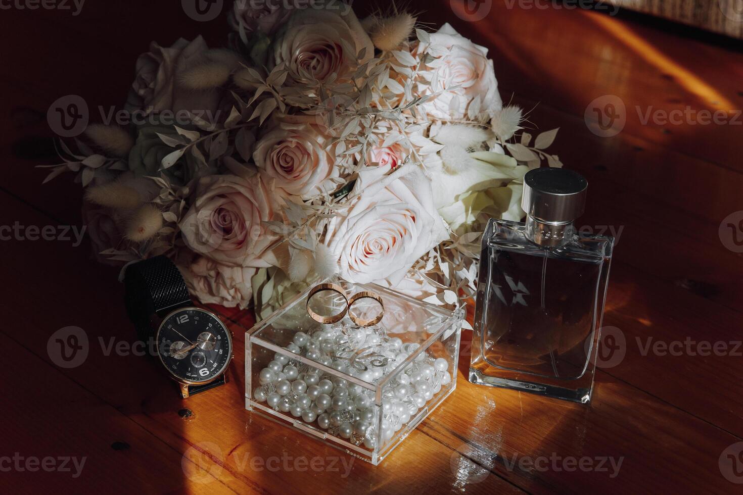 A bouquet of flowers and a watch are displayed on a wooden table photo
