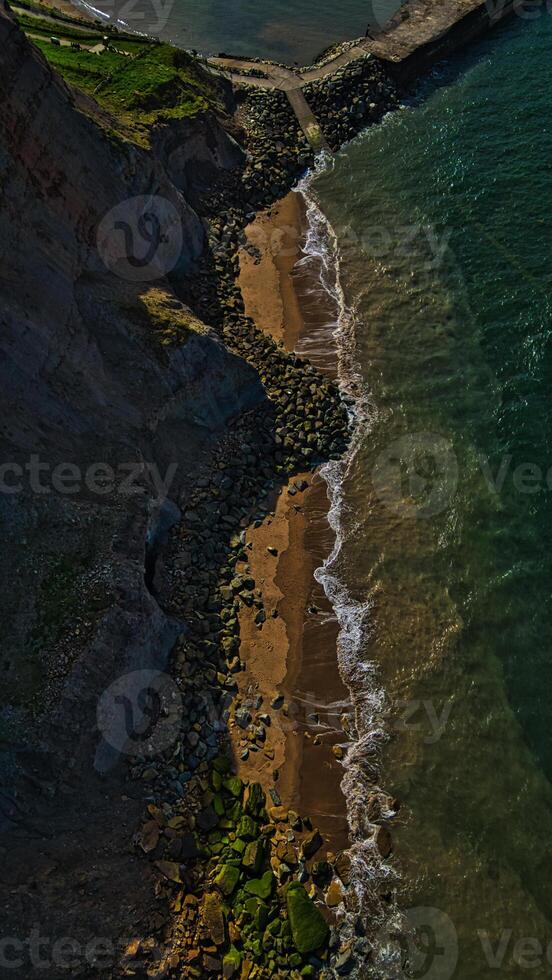 Aerial view of rocky coastline with cliff and breakwater photo