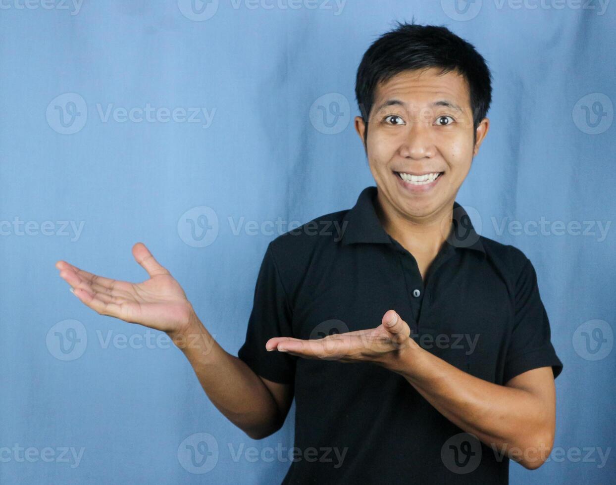Portrait of young Asian man smiling with open palm gesture advertising and product placement concept photo