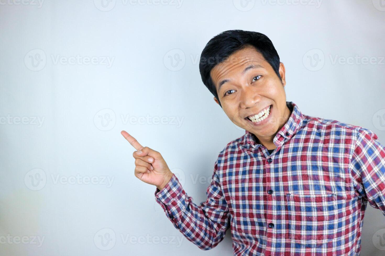 Asian man expression smiling while pointing to the side presenting the product. advertising concept photo