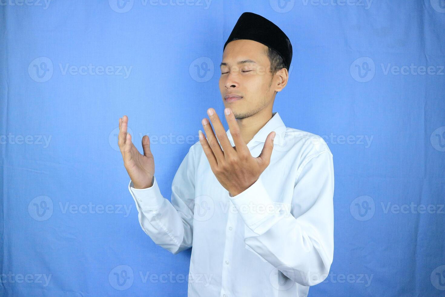 Muslim asian man holding prayer beads on blue background. Ramadan kareem and ied mubarak concept. photo