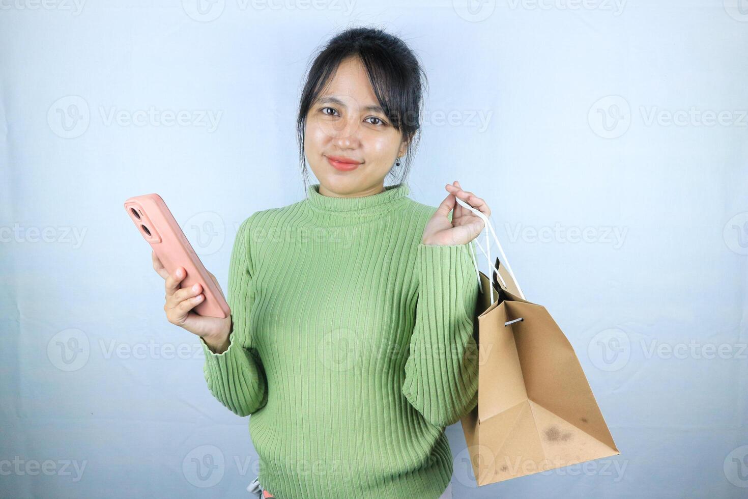 Beautiful Asian young girl holding a brown blank paper bag and makes purchases in an online store photo