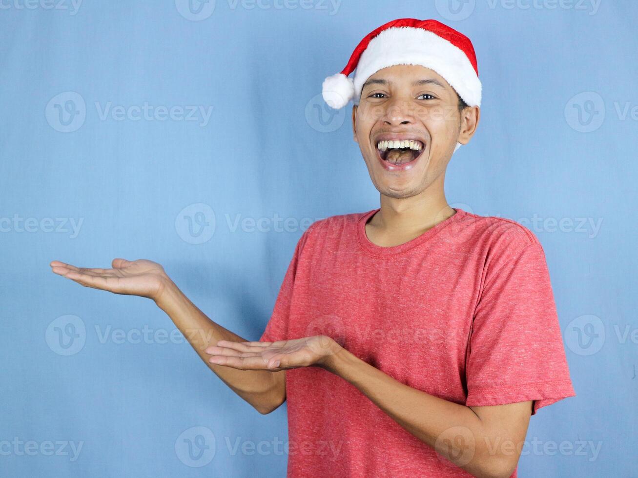 Handsome asian man in red christmas cap showing side and looking at camera. Christmas sale concept. photo