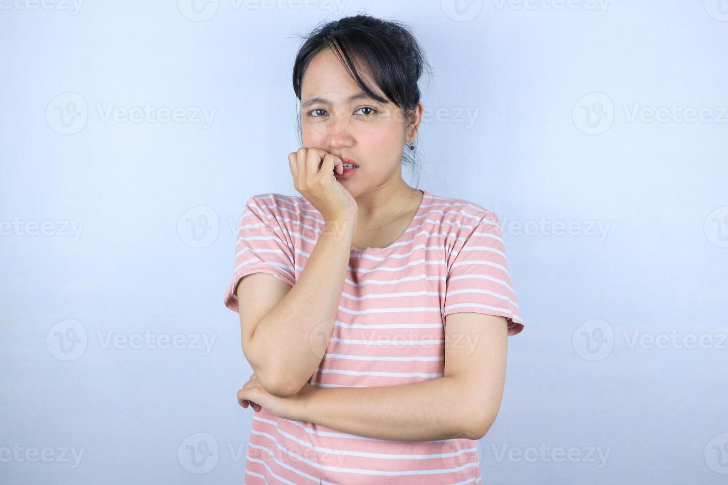 worried expression of beautiful asian woman looking at camera while biting finger photo