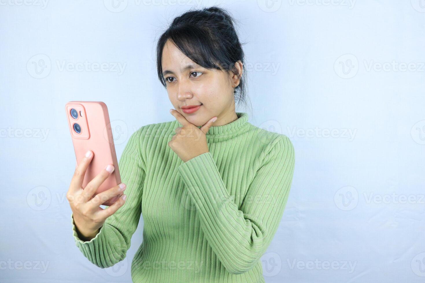 pensive expression of Asian woman holding smart phone on white background photo