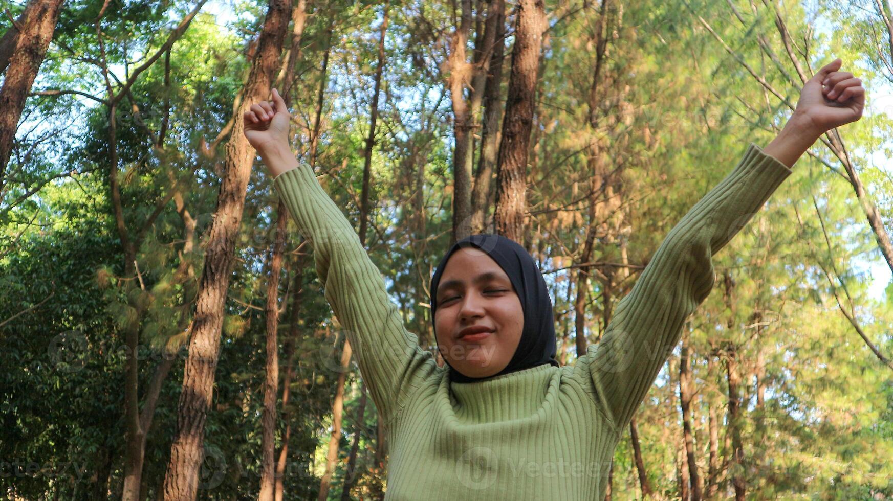 Enjoying the nature. Young muslim woman arms raised enjoying the fresh air in summer green park photo