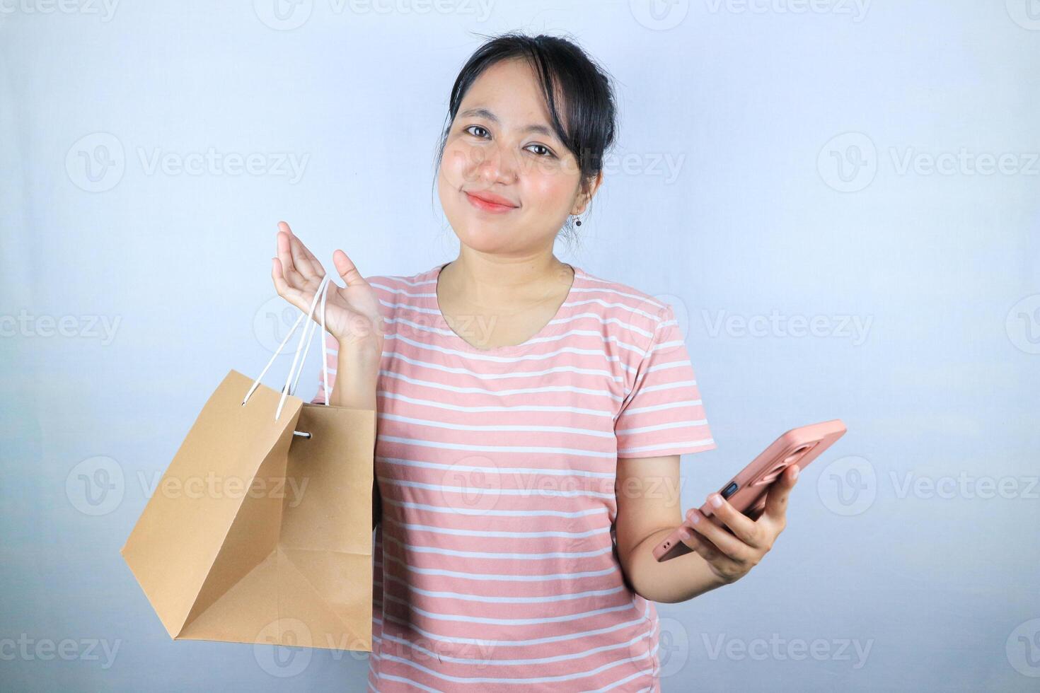 Smiling expression of Asian woman holding craft paper shopping bags and smart phone photo