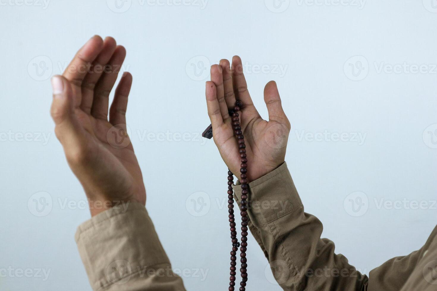 Male hand holding prayer beads rosary on white background. Ramadan kareem and ied mubarak concept. photo