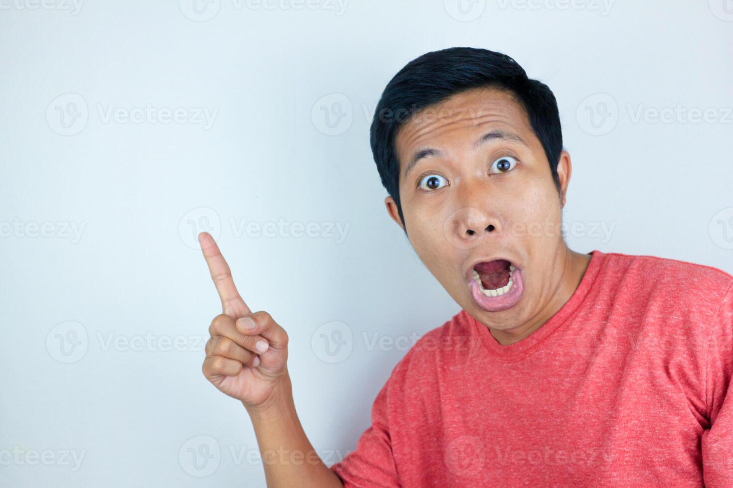 funny facial expression of asian man shocked and surprised while pointing at right side photo