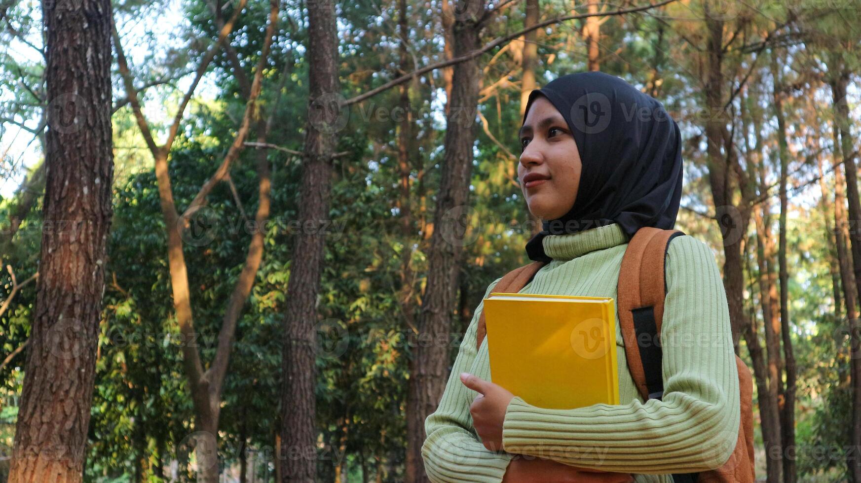young muslim Woman holds book in her hands. Reading the book in the park during morning sun photo