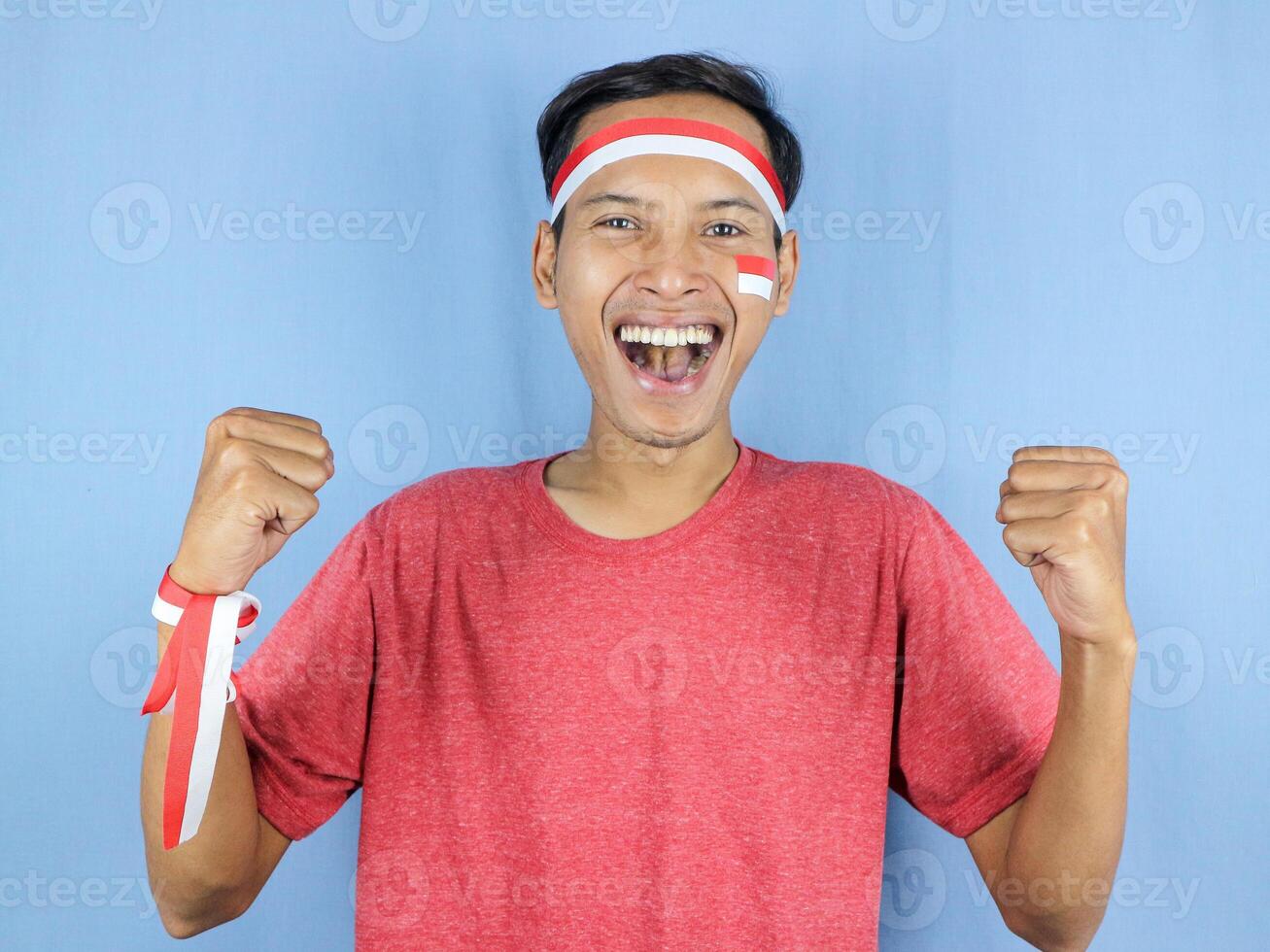 Excited expression young indonesian man wearing red and white headband with clenching fist gesture. photo