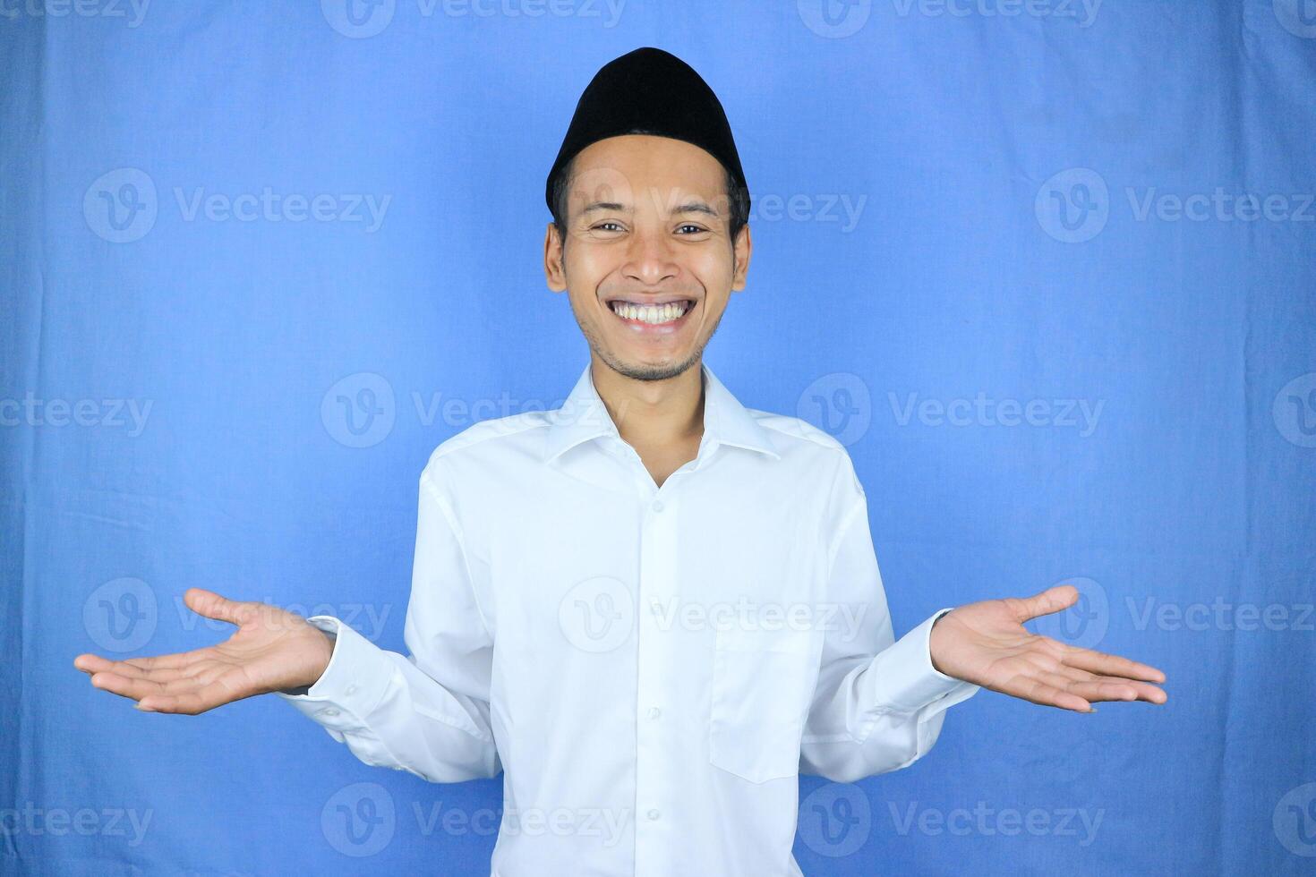 Smiling of excited muslim asian man wearing cap with open hand gesture photo