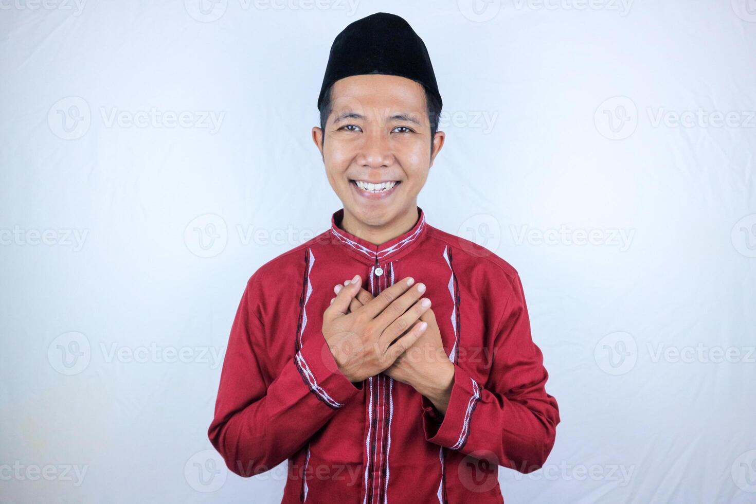 Smiling expression of Asian Muslim man welcoming Ramadan celebration with hands on chest photo