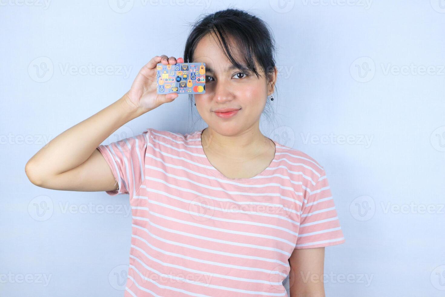 Smiling face expression of beautiful asian young woman showing credit card on white background photo