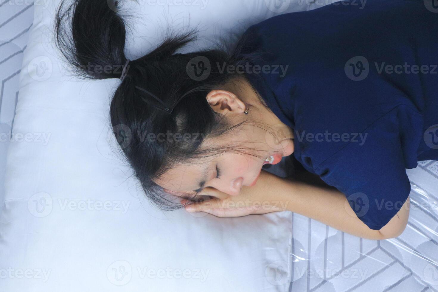 Tired beautiful Asian woman yawning in bed. Bedtime concept photo