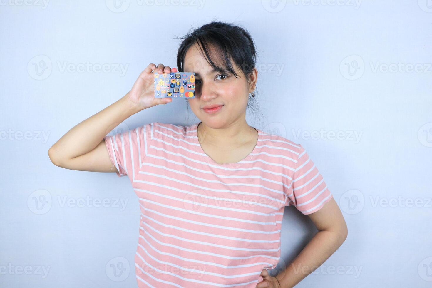 Smiling face expression of beautiful asian young woman showing credit card on white background photo