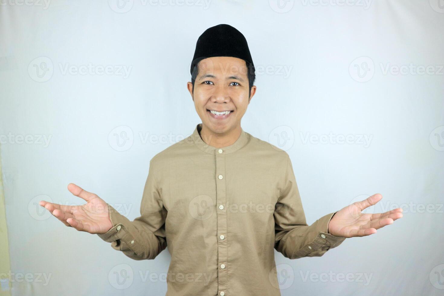 Smiling of excited muslim asian man wearing cap with open hand gesture photo