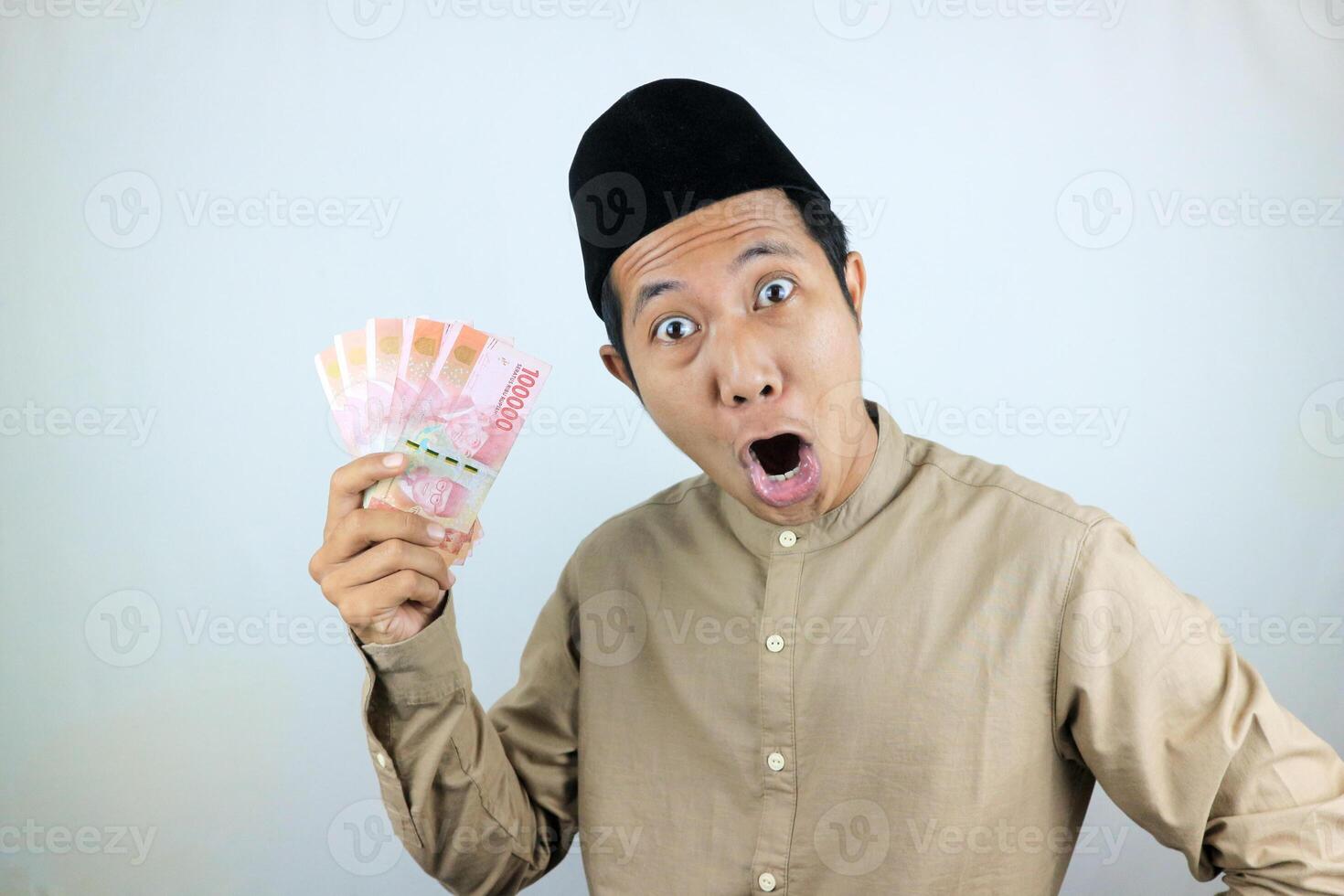 funny facial expression shocked and surprise asian muslim men wearing cap while holding money photo