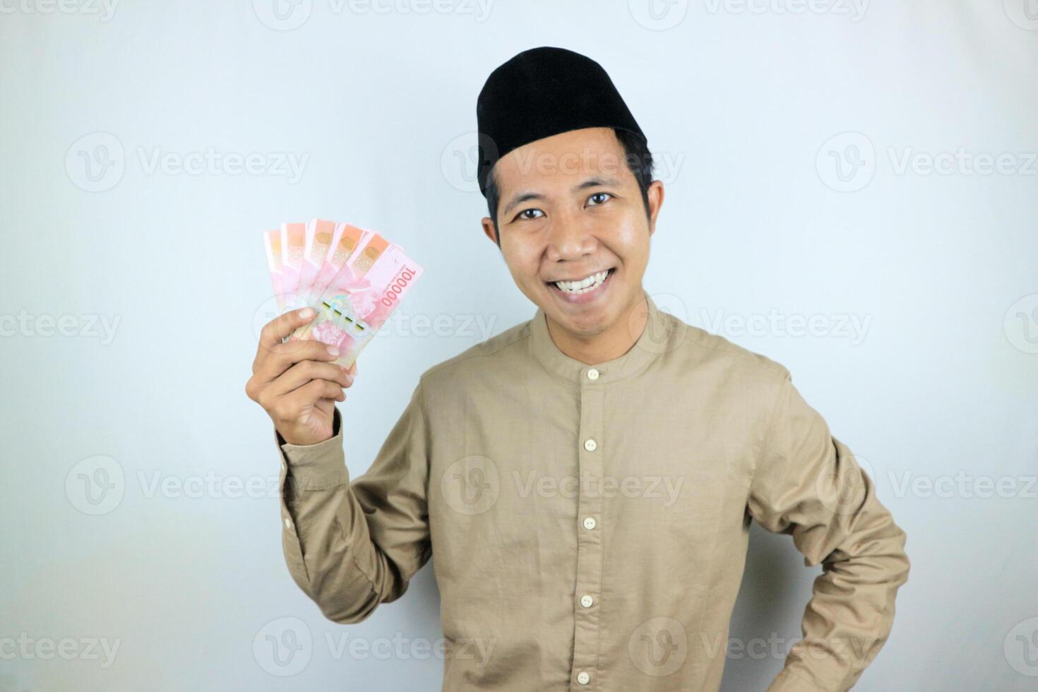 Happy expression of Asian Muslim man holding money rupiah banknotes isolated on white background photo