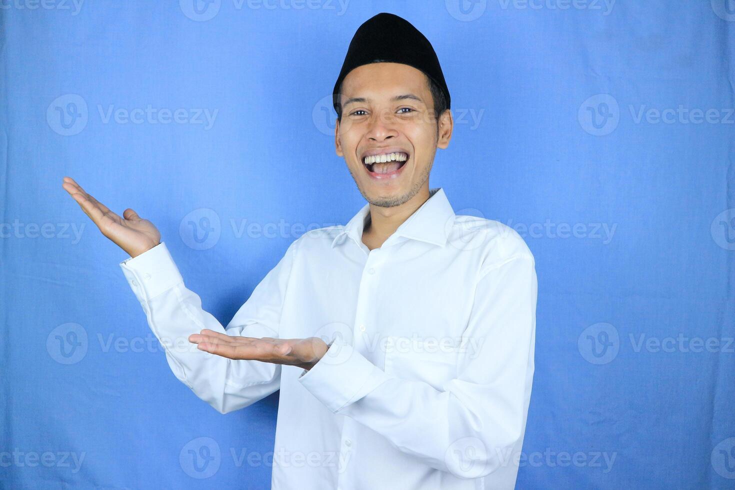 Smiling expression of muslim asian man, presenting and showing an empty space. Advertising concept photo