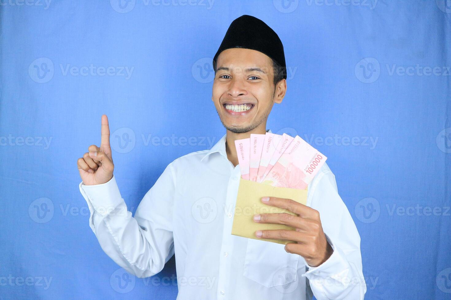 Happy expression of Asian Muslim man holding money rupiah banknotes isolated on white background photo