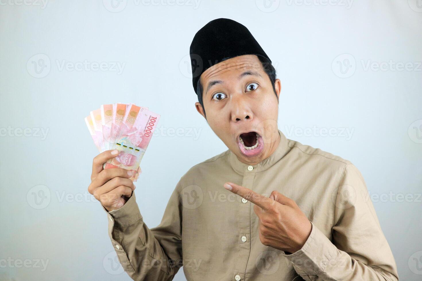 funny facial expression shocked and surprise asian muslim men wearing cap while holding money photo