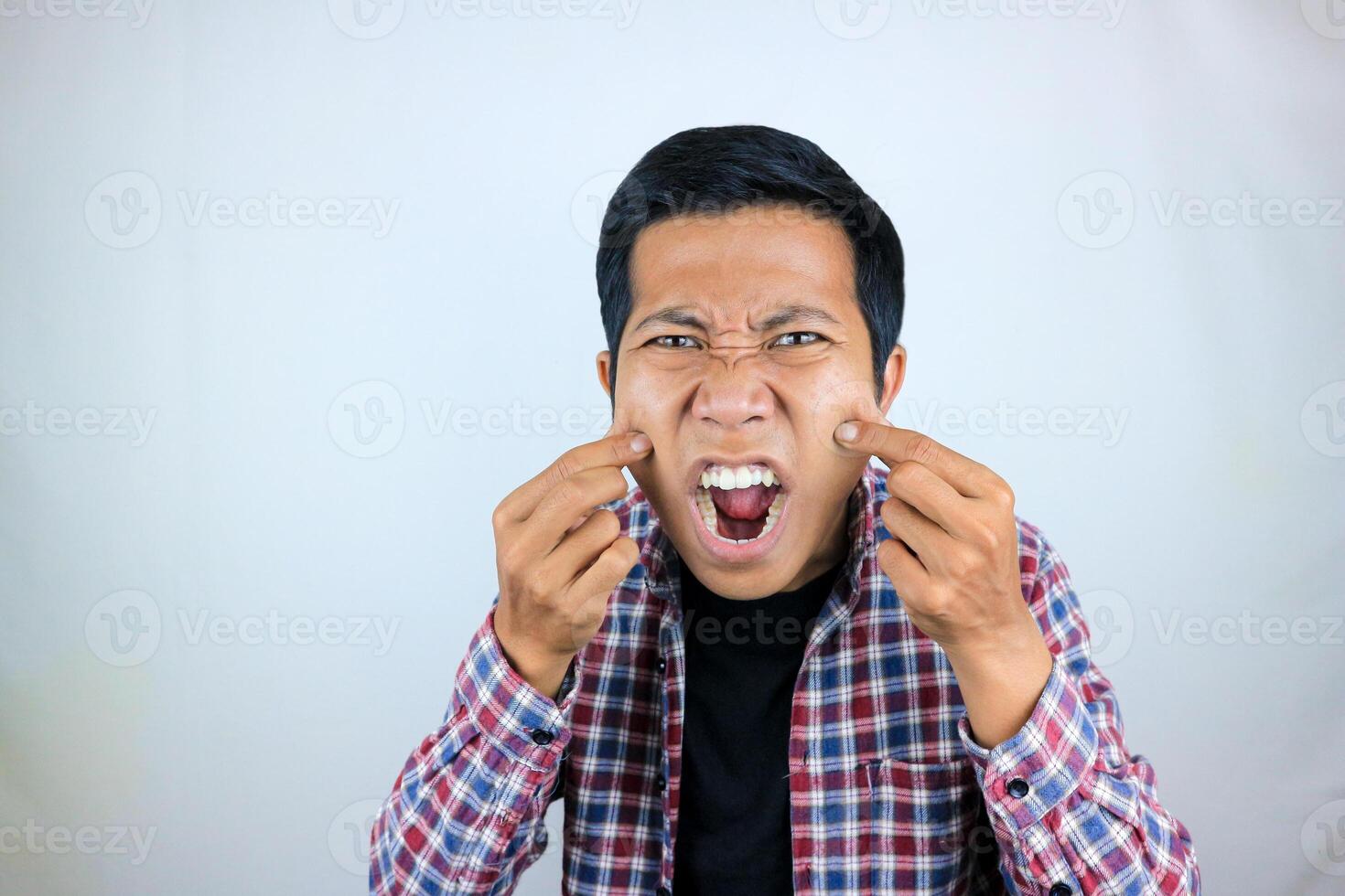 Asian man's annoyed expression touches his cheek because he is chubby photo