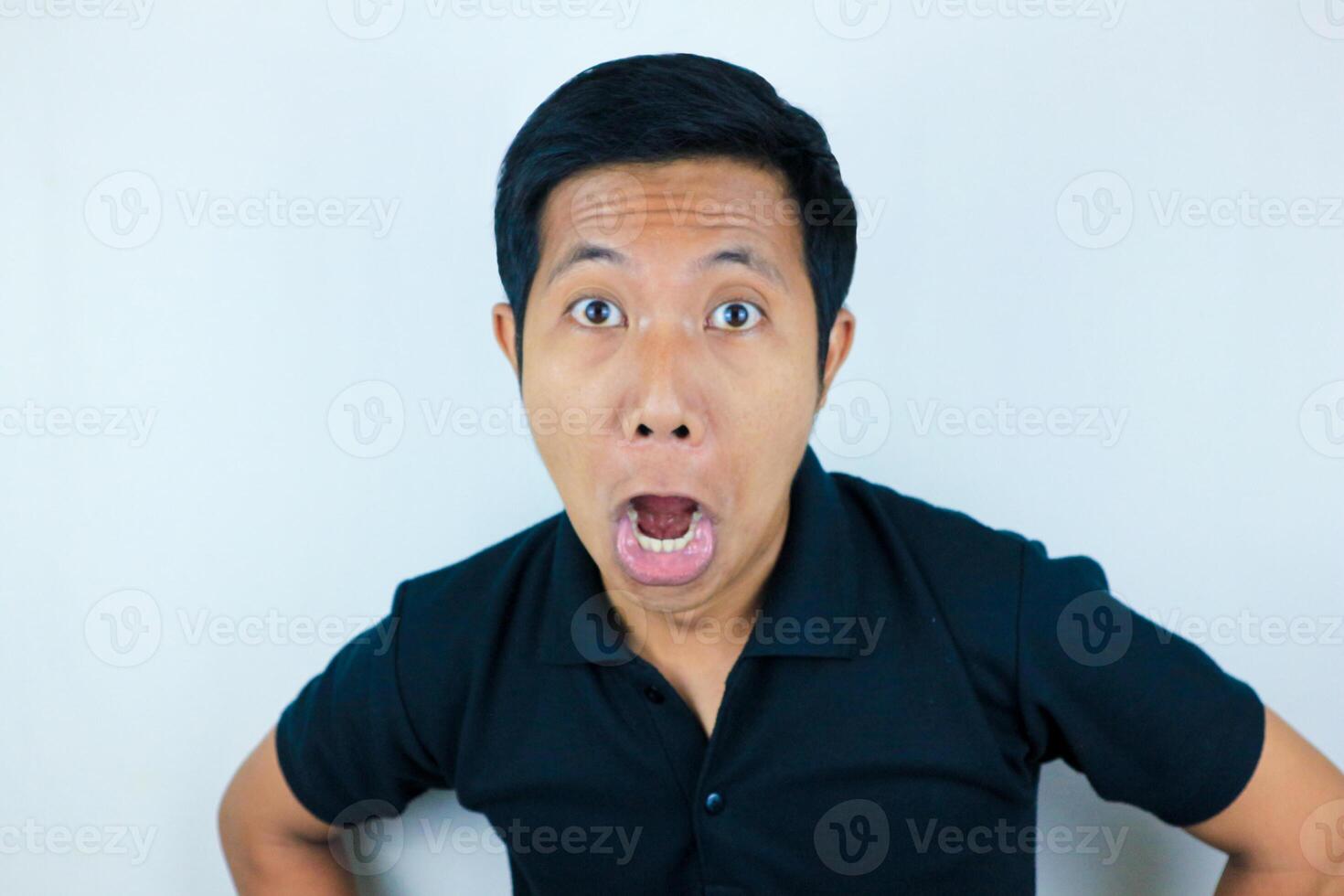 funny expression of shocked and surprised Asian man wearing a black t-shirt looking at the camera photo
