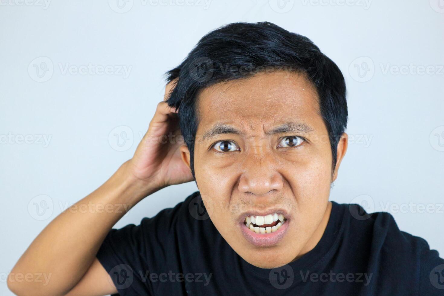 funny facial expression of asian man confused and scratching his head, questioning the problem photo