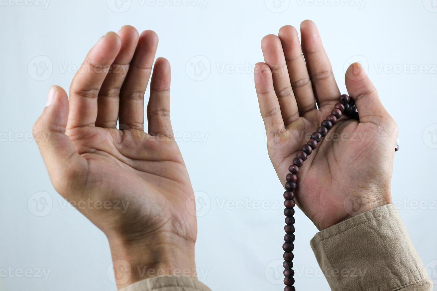 Male hand holding prayer beads rosary on white background. Ramadan kareem and ied mubarak concept. photo