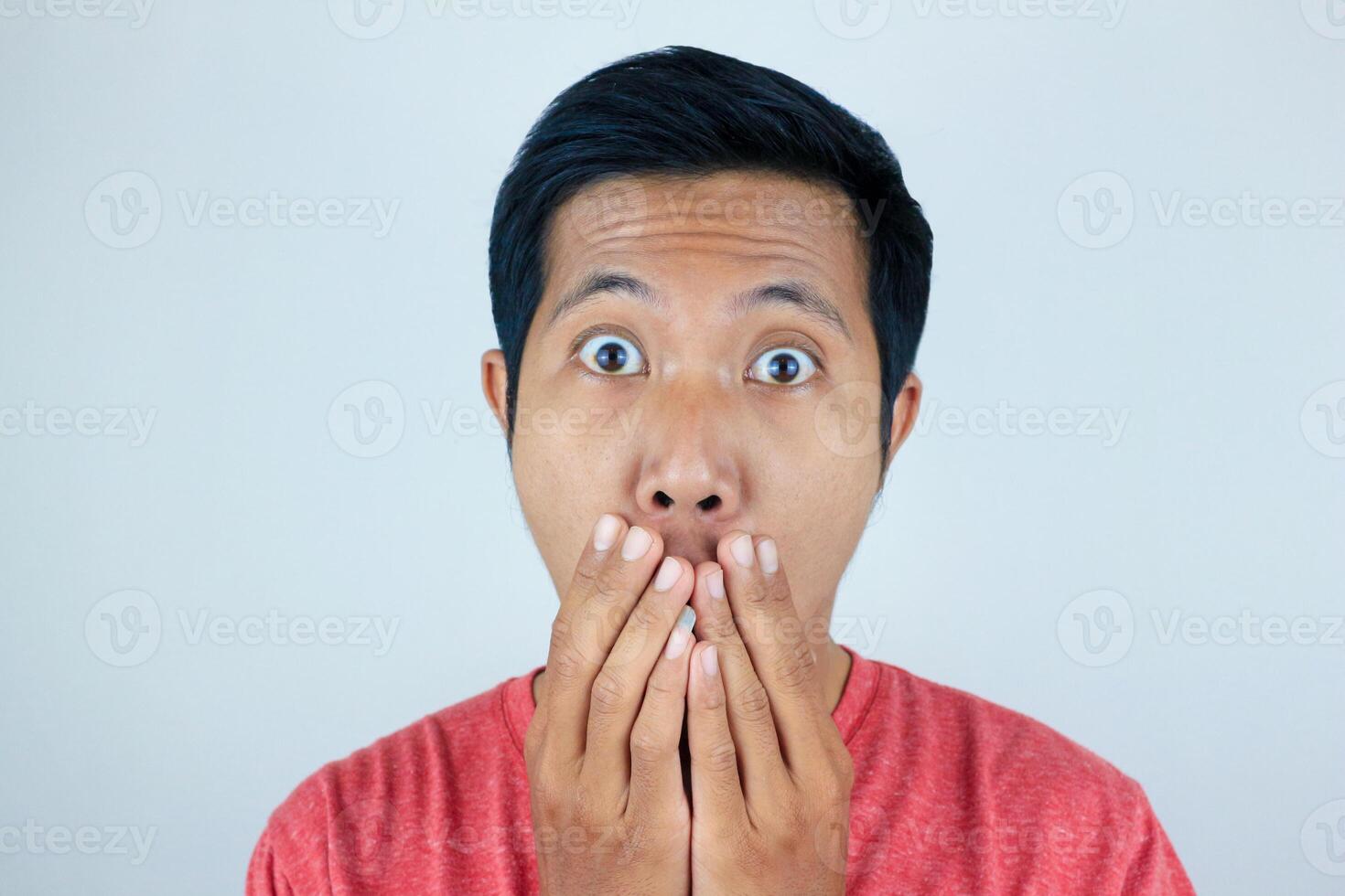 funny expression of shocked and surprised Asian man wearing a red t-shirt looking at the camera photo
