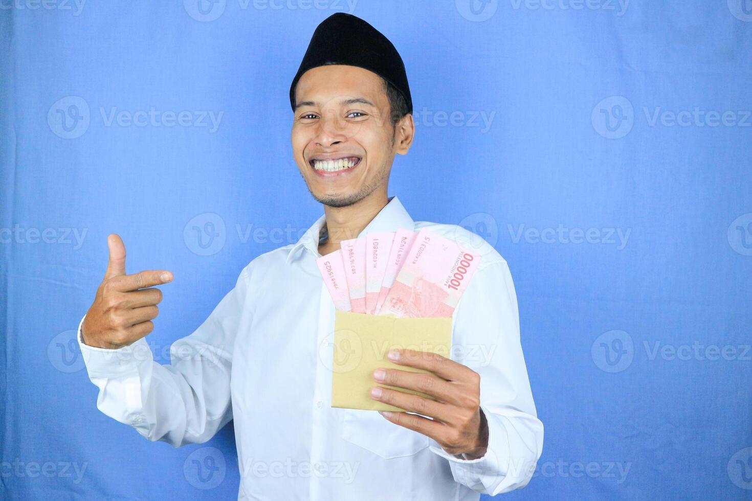Happy expression of Asian Muslim man holding money rupiah banknotes isolated on white background photo