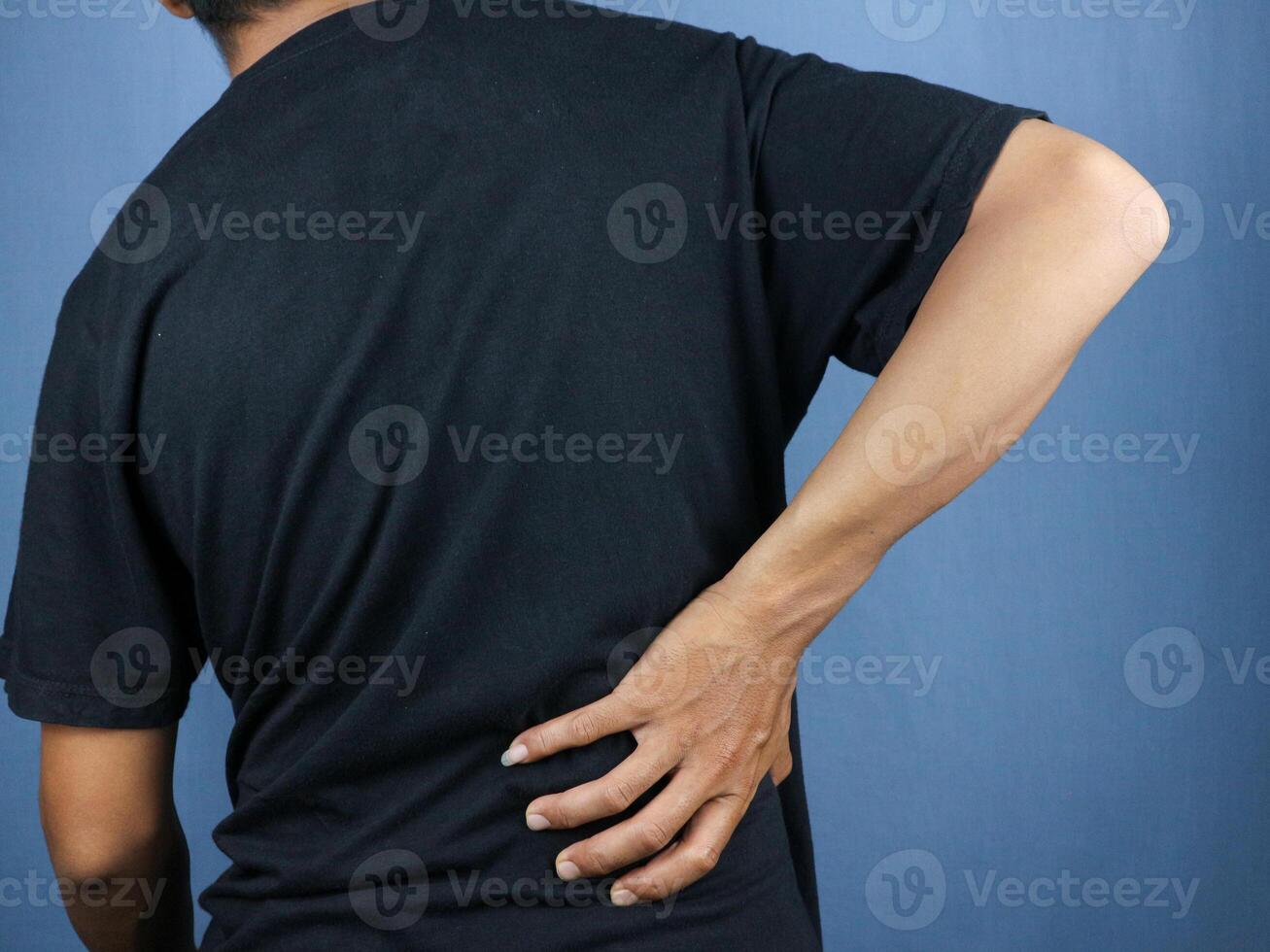 Close-up rear view of man's hand touching back pain, low back pain concept. photo