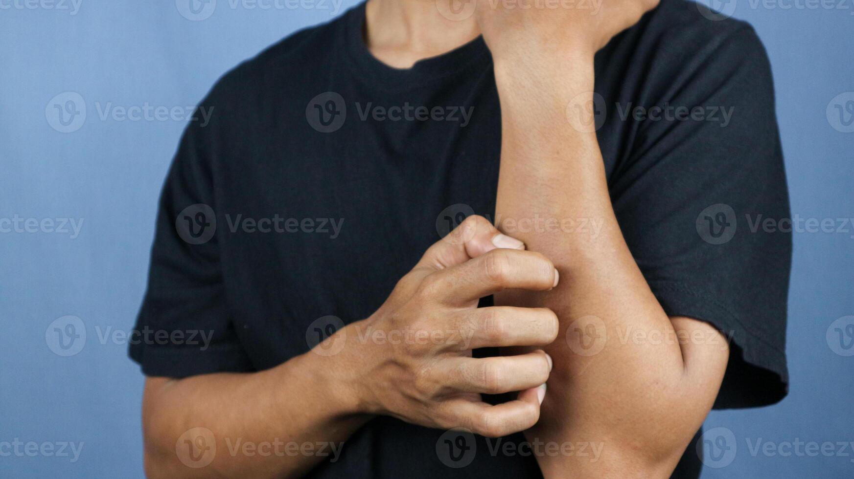 Asian young man scratching his hand isolated on blue background. photo