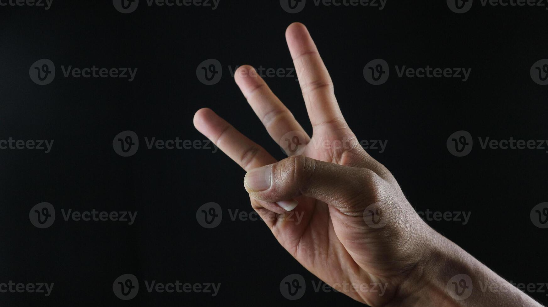 Male hand gesture number three closeup isolated on a black background photo