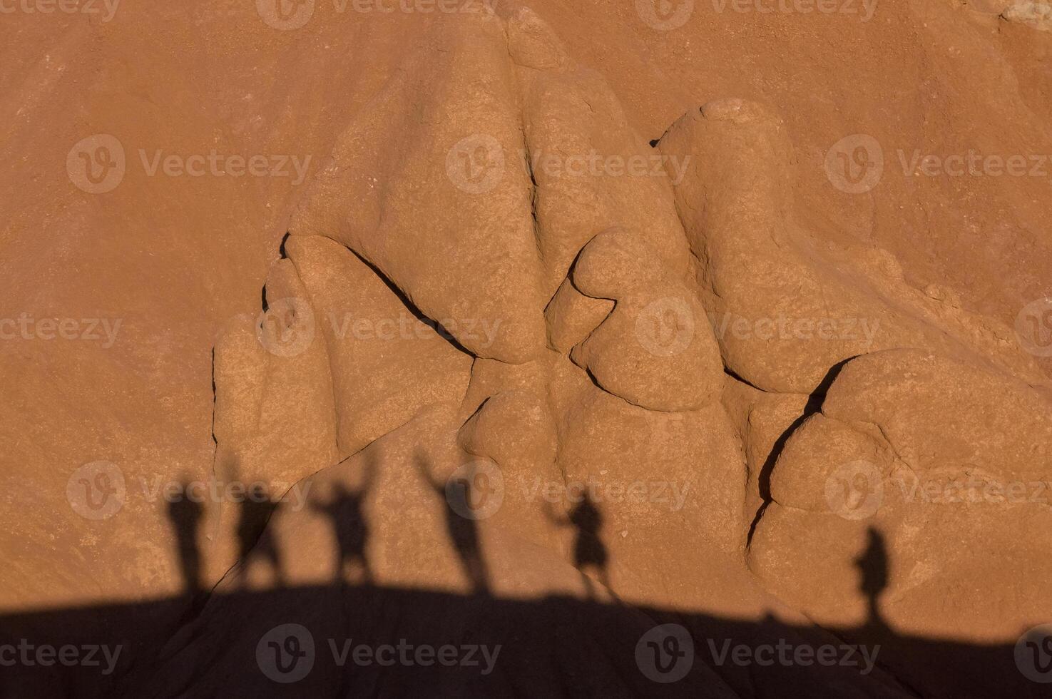 The elongated shadows of tourists traverse the undulating canyon walls, a stark contrast of human vivacity against the still, enduring formations sculpted by the relentless forces of nature over time. photo