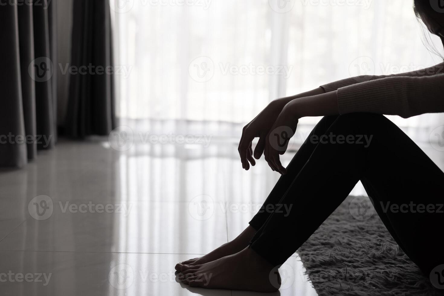 Depressed woman, Silhouette of teenager girl with depression sitting alone in the dark room. Black and white photo. photo
