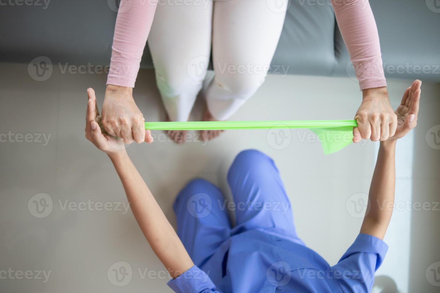 female doctor using elastic bands help patient regain muscle movement after recuperating from muscle injury and wants rehabilitate her be able use her normal daily life by practicing physical therapy photo