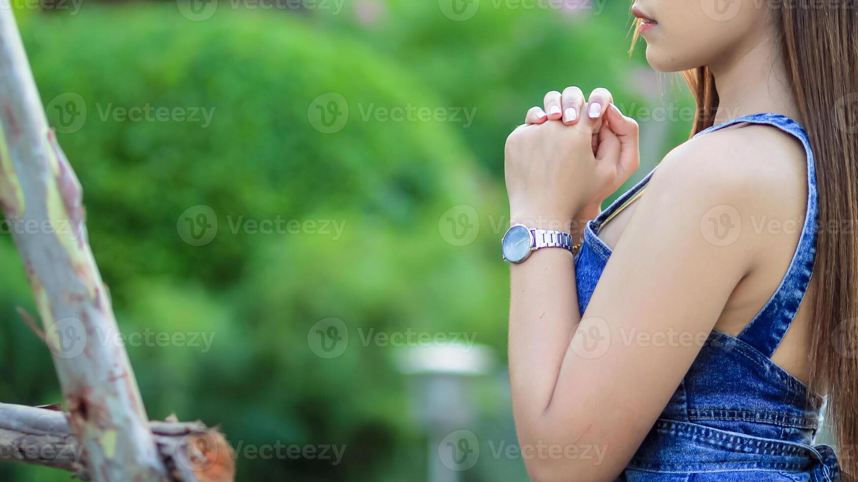 young woman clasped her hands together in prayer asking for forgiveness from God based on her Christian beliefs and faith in God teachings. concept prayer and intercession according beliefs about God photo