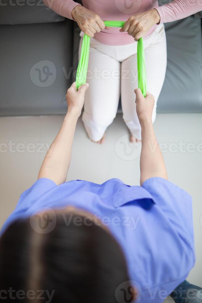 female doctor using elastic bands help patient regain muscle movement after recuperating from muscle injury and wants rehabilitate her be able use her normal daily life by practicing physical therapy photo